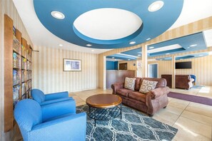 Una sala de estar moderna con un sofá azul, un sofá de cuero marrón y una mesa de centro redonda.