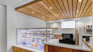 Mostrador moderno de panadería con una vitrina de pasteles y un panel de menú digital.