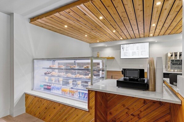 A modern bakery counter with a display case of pastries and a digital menu board. - The Evergreen Hotel (McCall)
