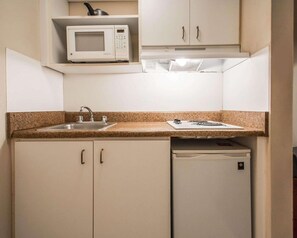 Una cocina compacta con microondas, lavamanos y refrigerador.