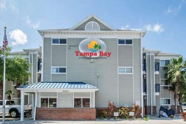 Un hôtel de la chaîne Tampa Bay Extended Stay, reconnaissable à son grand panneau, à son entrée abritée et à sa façade en briques.