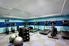 Un gimnasio con cintas de correr, elípticas y pesas libres.