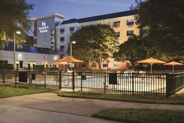 Un hotel Hyatt con piscina, rodeado de una valla y árboles.