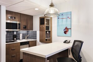 Een moderne keuken met inbouwapparatuur, een wit aanrecht en een hanglamp.