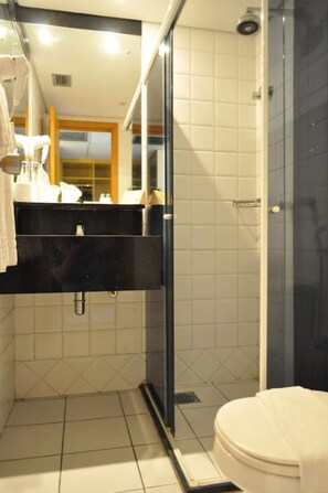 Une salle de bain comprenant des toilettes, un lavabo avec un miroir et un espace douche.