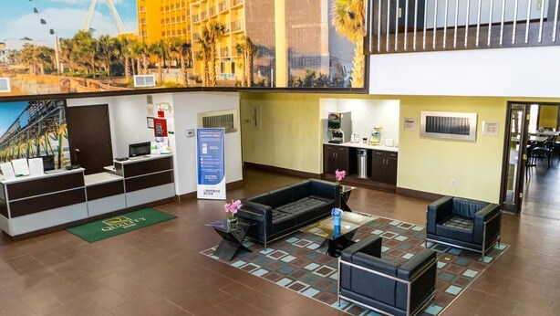 A hotel lobby with a reception desk, seating area, and a view of a cityscape including a Ferris wheel. - Quality Inn Whiteville North (Whiteville)
