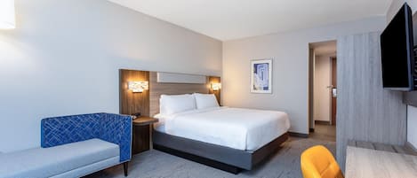 A hotel room with a bed, a sofa, a desk, and a TV.