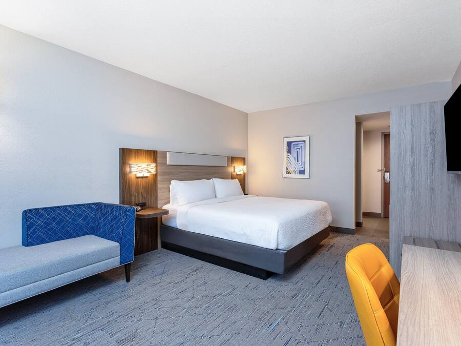 A hotel room with a bed, a sofa, a desk, and a TV.