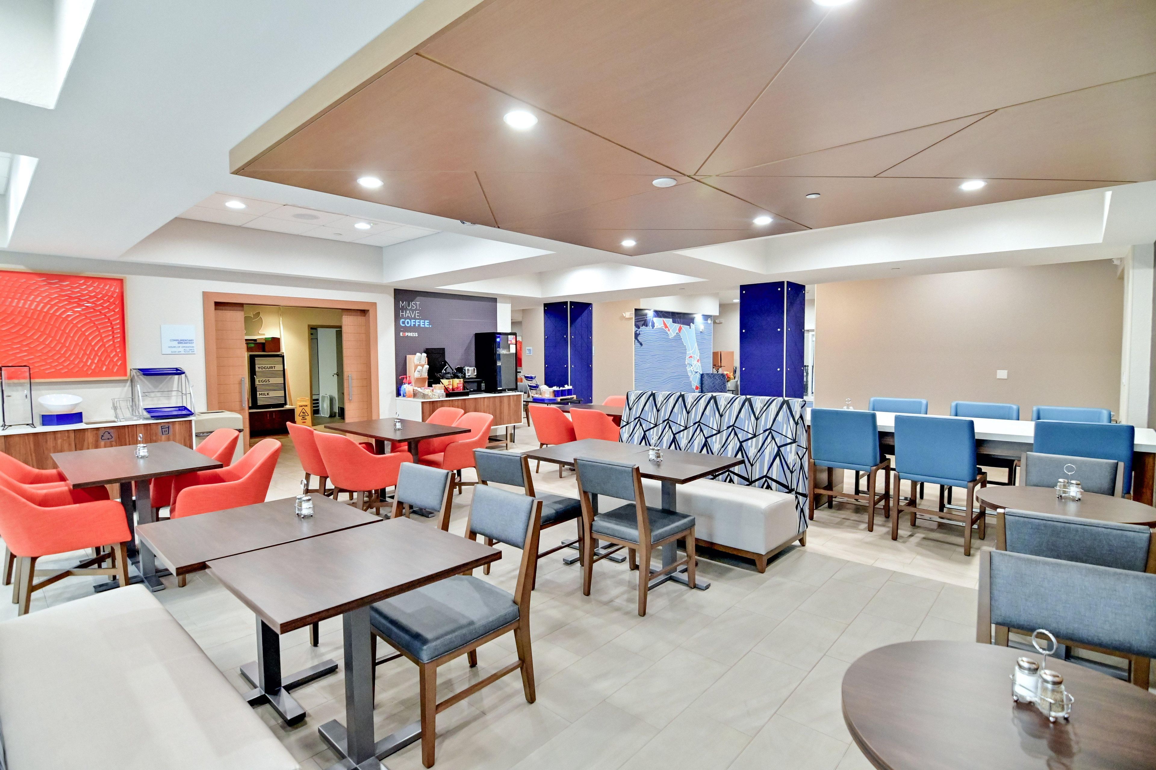 A modern restaurant with multiple seating areas, including tables and booths, and a counter for ordering.