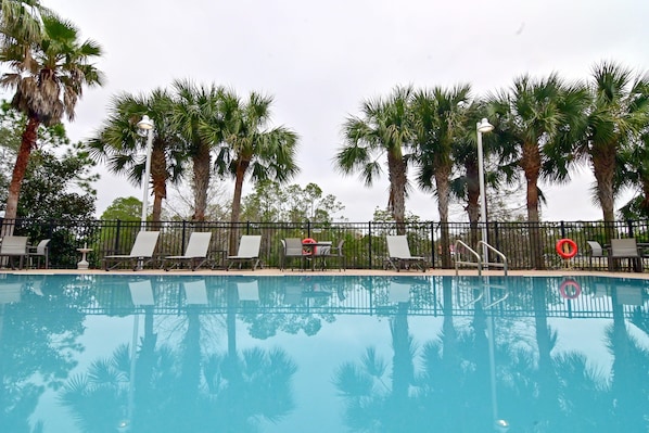 A swimming pool with lounge chairs and palm trees. - Holiday Inn Express & Suites Palm Coast - I-95 (Palm Coast)