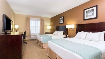 A hotel room with two beds, a desk with a TV, a chair, and a window with curtains.