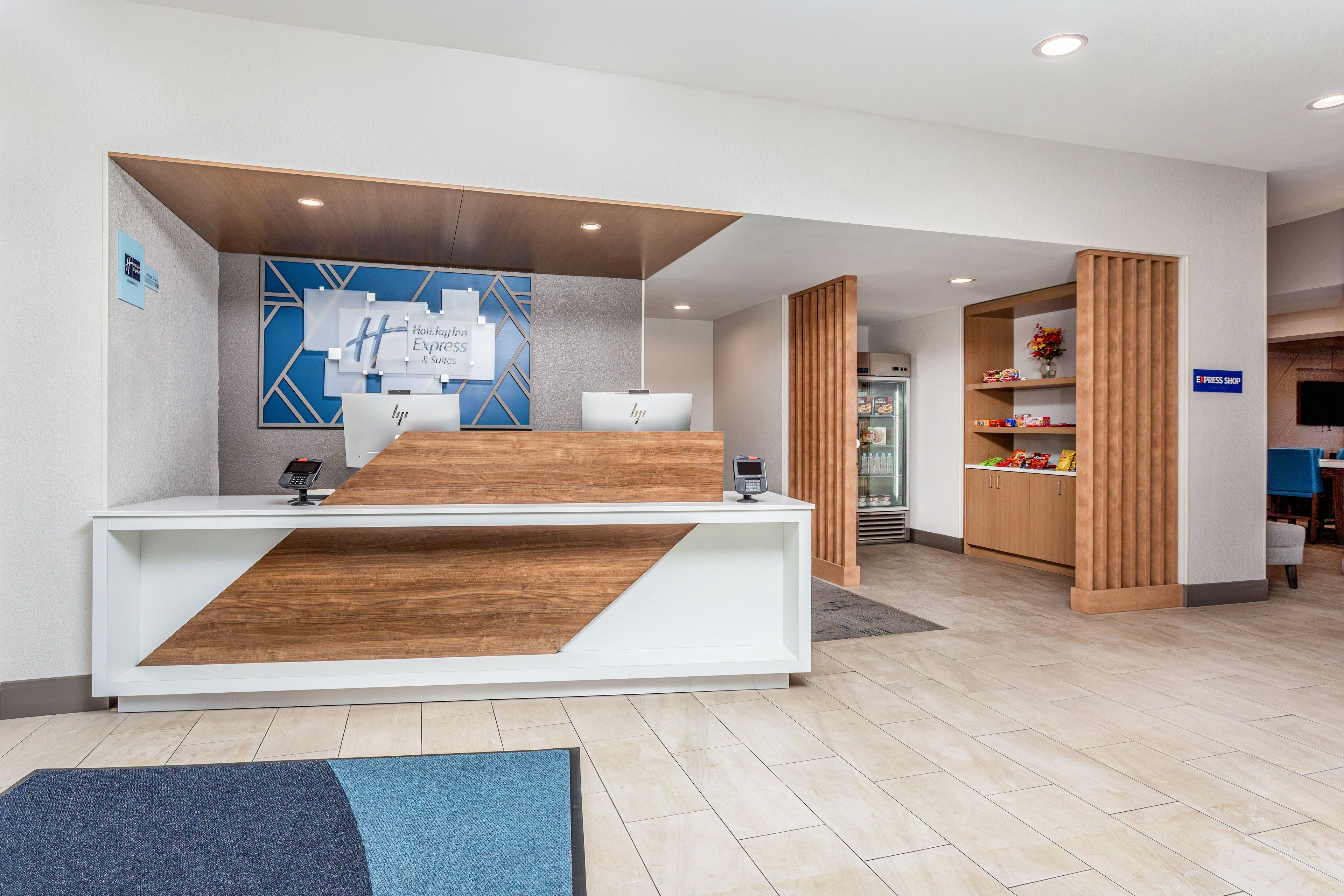 A reception desk with a modern design, a blue wall with geometric patterns, and a sign indicating an E-Press Shop.