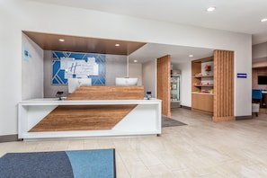 Un mostrador de recepción de diseño moderno, una pared azul con patrones geométricos y un letrero que indica una tienda E-Press.
