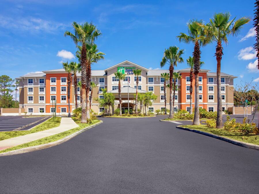 A hotel with a central entrance, multiple floors, and a parking lot.