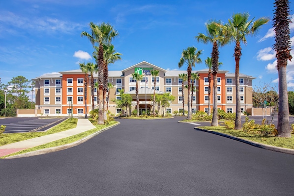 A hotel with a central entrance, multiple floors, and a parking lot.
