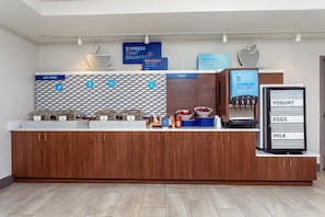 A breakfast station with hot food, fruit, and a yogurt machine. - Holiday Inn Express & Suites Palm Coast - I-95 (Palm Coast)