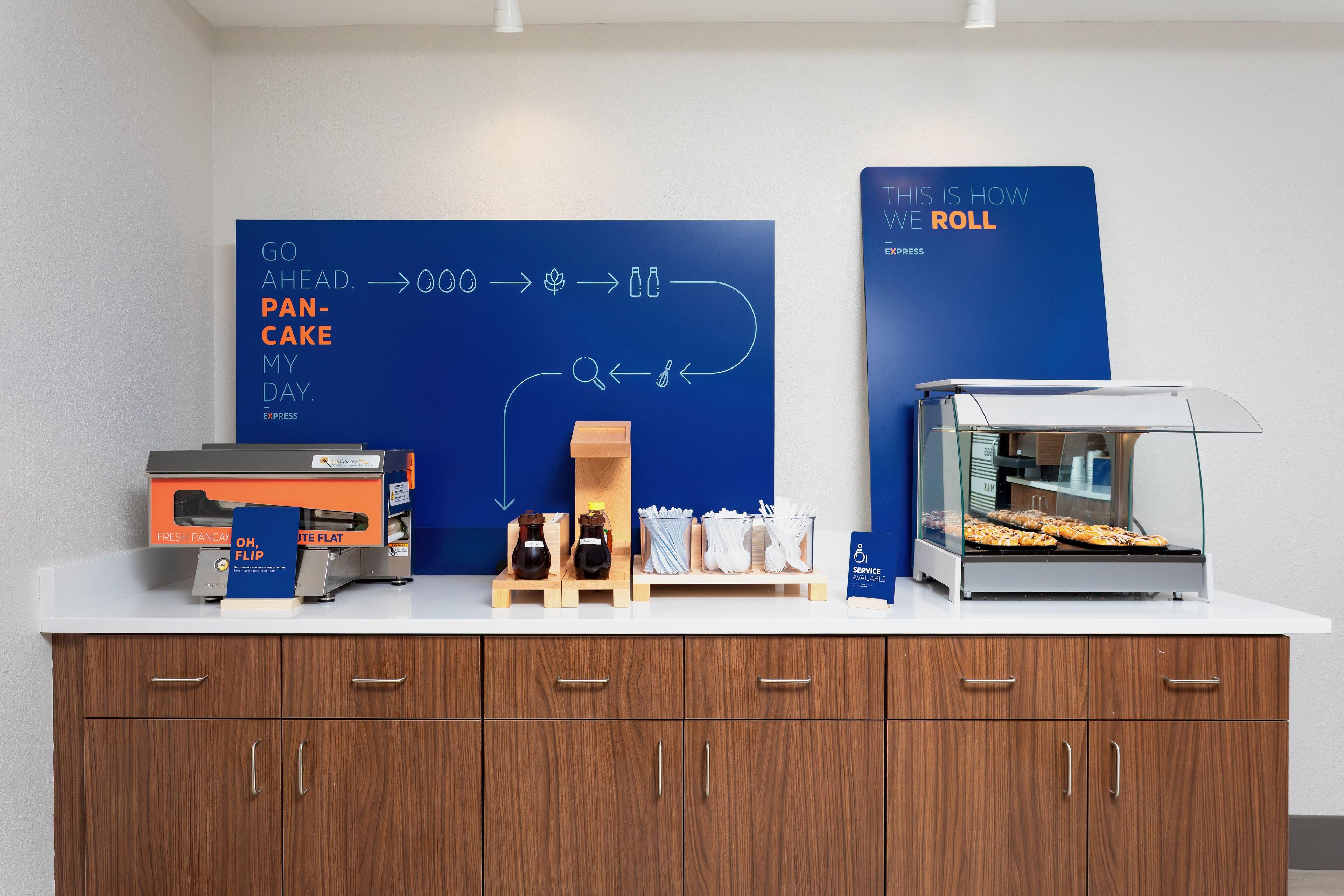 Een ontbijtstation met een panini-grill, een doos verse panini en een presentatie van ontbijtartikelen.