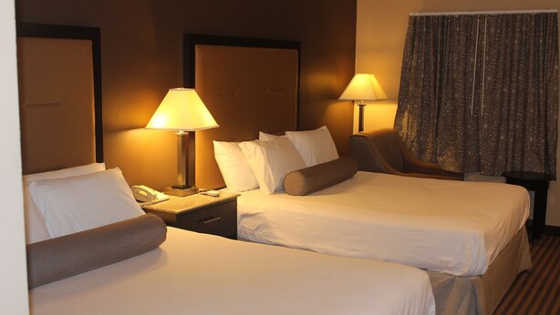 Ein Hotelzimmer mit zwei Betten, einem Nachttisch mit Telefon und zwei Lampen.