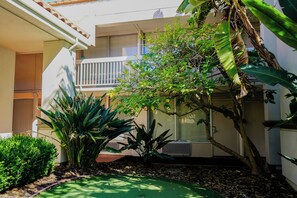 A residential building with a balcony, surrounded by various plants and a small lawn area. - Uptown Oasis San Jose Airport (San Jose)