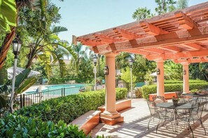 A covered outdoor area with a pool, seating, and greenery. - Uptown Oasis San Jose Airport (San Jose)