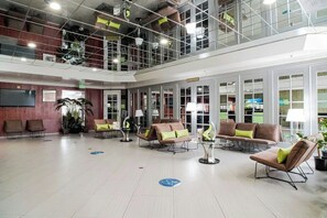 A spacious lobby with seating areas, a television, and a staircase leading to an upper level. - Uptown Oasis San Jose Airport (San Jose)