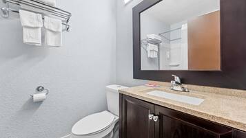 A bathroom with a toilet, a sink, a mirror, and a towel rack.