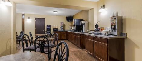 Cocina compacta con comedor, equipada con cafetera, microondas y refrigerador.