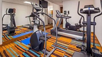 A hotel gym with various exercise equipment including treadmills, elliptical machines, and a stationary bike.