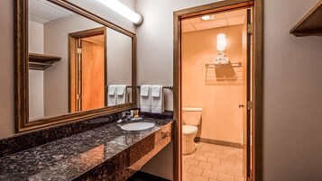 Un baño con lavamanos de mármol, inodoro y espejo.