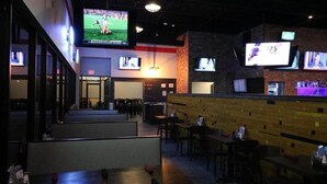 Um bar esportivo com várias telas, cabines e um balcão.