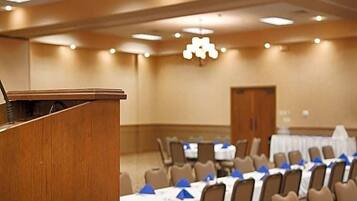 A conference room with a podium, tables with blue tablecloths, and chairs.