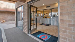 A hotel entrance with a glass door, a reception desk, and a visible outdoor area with a trash bin. - Motel6 Willcox, AZ (Willcox)