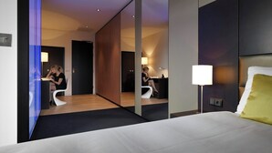 Una habitación de hotel moderna con una cama grande, un escritorio y un espejo.