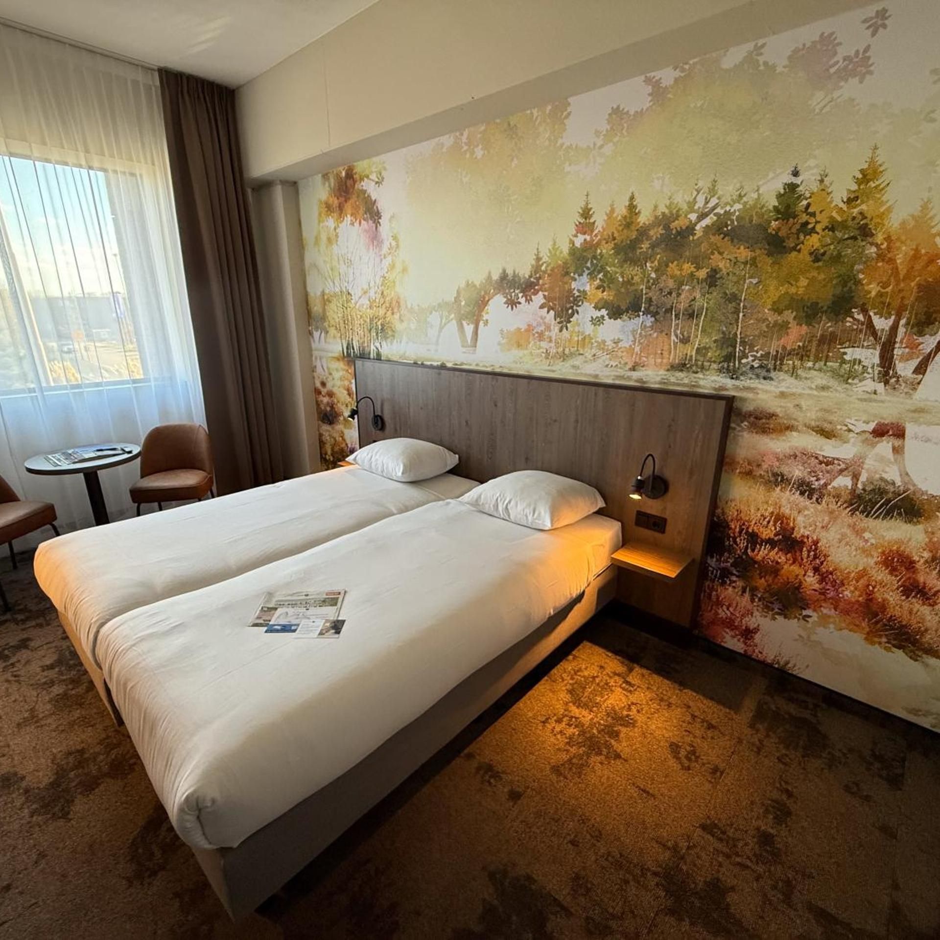 Een hotelkamer met twee bedden, een tafeltje en een stoel.