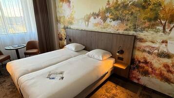 Een hotelkamer met twee bedden, een tafeltje en een stoel.