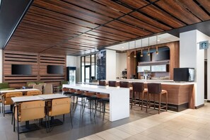 Une cuisine moderne dotée d’un îlot central, de tabourets de bar et d’un coin repas avec des tables et des chaises.