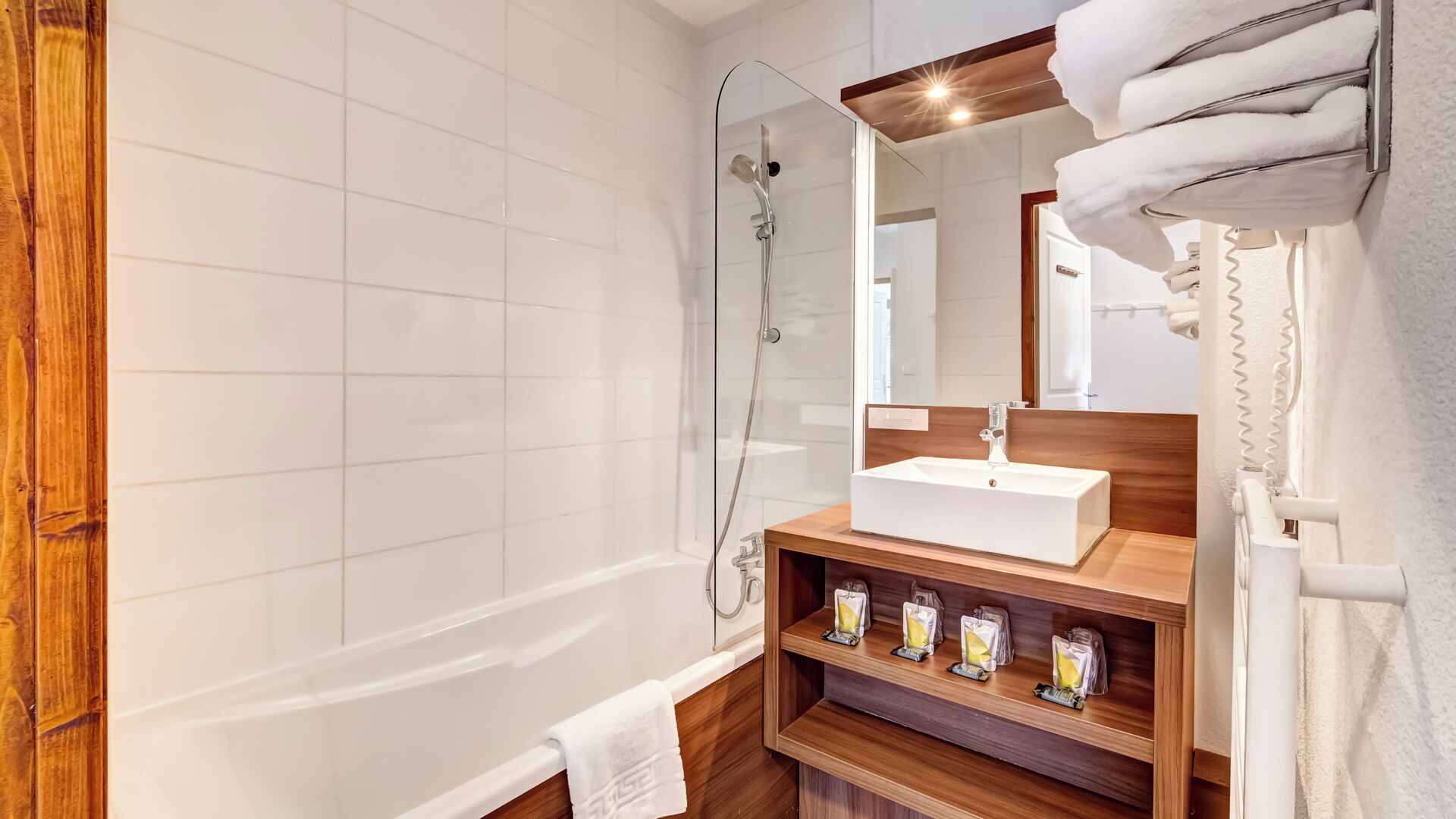 A modern bathroom with a glass-enclosed shower, a wooden vanity with a sink, and a towel rack.