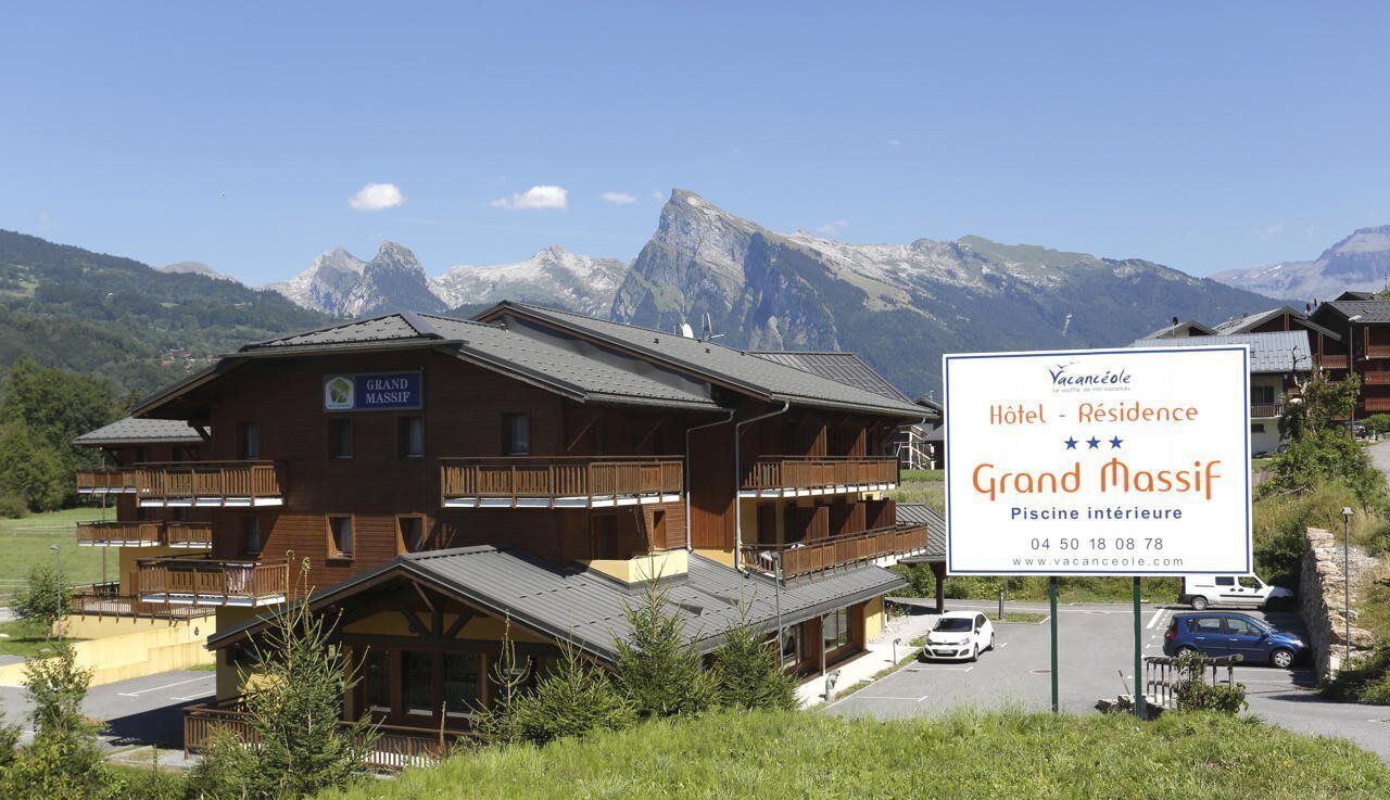A hotel named Grand Massif with a signboard indicating it offers a swimming pool and a contact number.
