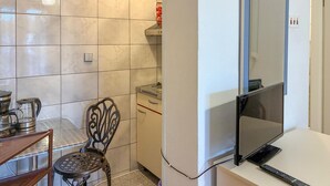 Une cuisine compacte comprenant une table à manger, une chaise, une cuisinière et un téléviseur.
