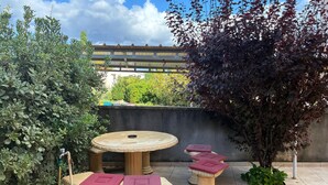 A patio with a round table and two cushioned chairs, a hose, and a tree. - Nice apartment in Lopar with WiFi (Lopar)
