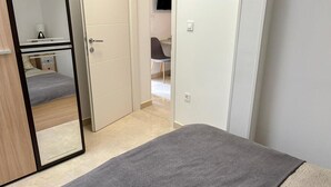Et soveværelse med seng, garderobeskab og spejl.