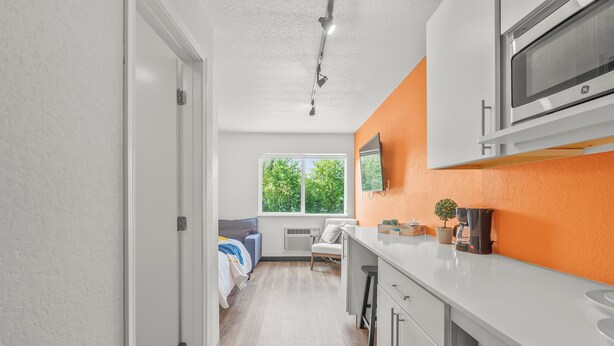 Une cuisine moderne avec des meubles blancs, un four à micro-ondes et une fenêtre donnant sur des arbres.