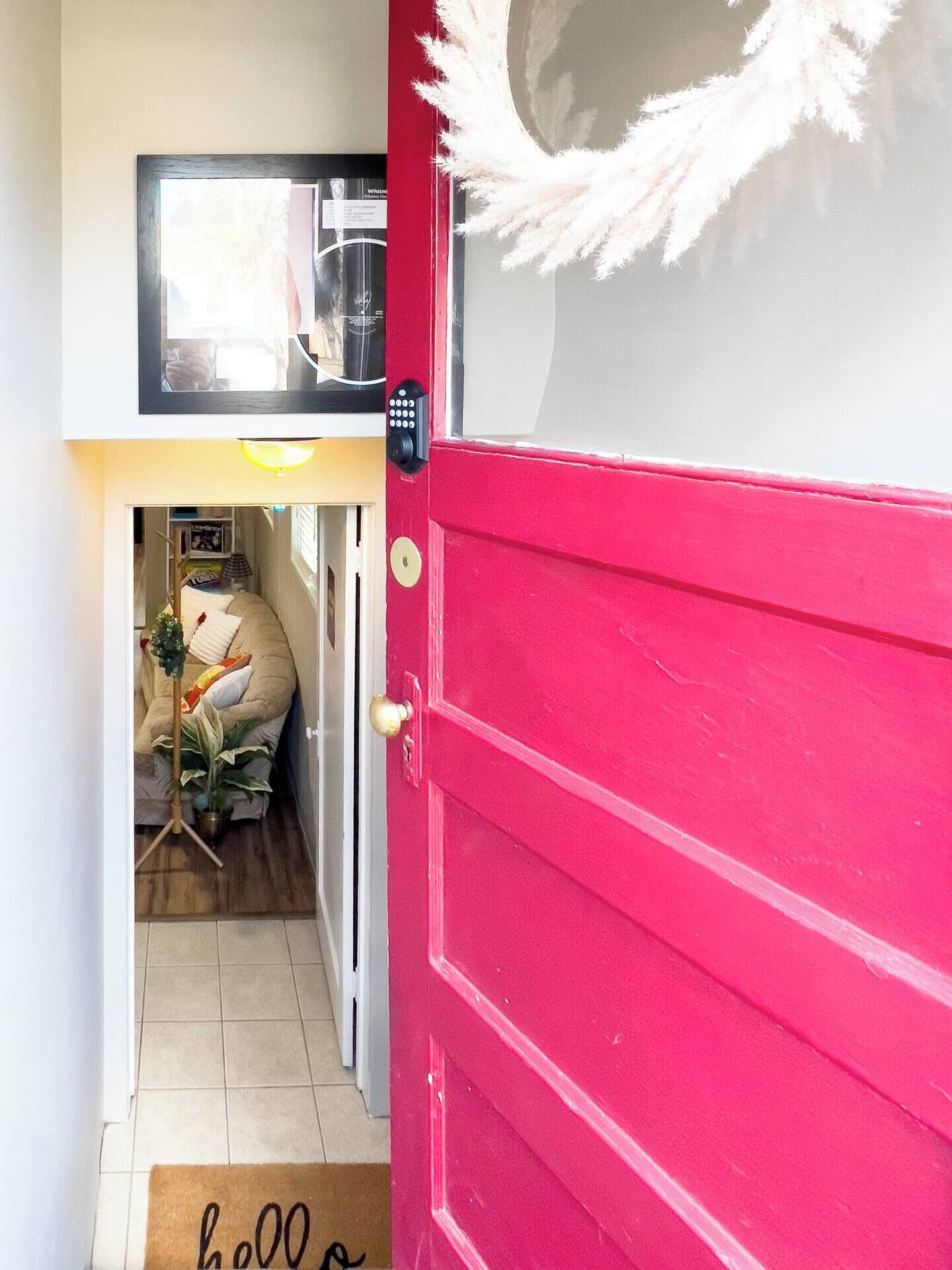 A red door with a doormat that reads "hello" and a keyhole.