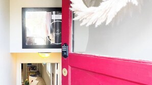 Una puerta roja con un felpudo que dice “hello” y una mirilla.