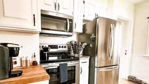 A modern kitchen with stainless steel appliances, white cabinets, and a wooden countertop. - Amazing 3-Bed Cottage with Spa, Home Office & Gym (Idaho Falls)