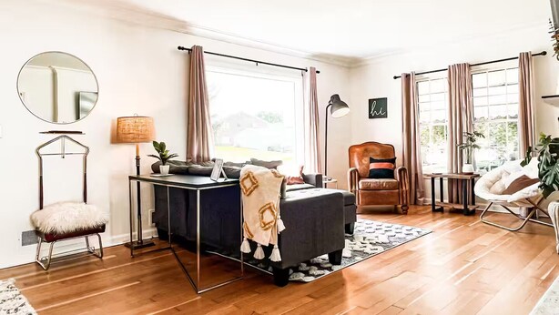 A modern living room with a sofa, armchair, and a small table with a lamp. - Amazing 3-Bed Cottage with Spa, Home Office & Gym (Idaho Falls)
