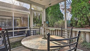 Eine überdachte Terrasse mit einem runden Tisch und Stühlen, umgeben von einem Metallgeländer.