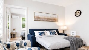 Une chambre à coucher avec un lit, une table de chevet, une horloge murale et un tableau.