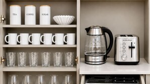 Une cuisine équipée d’étagères de rangement, d’une machine à café, d’un grille-pain et d’un tiroir contenant des couverts.