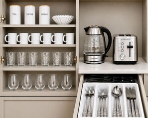 A kitchen with storage shelves, a coffee maker, a toaster, and a drawer with cutlery. - Elegant 2 Bed 2 Bath • Downtown • Free Parking (Hot Springs)